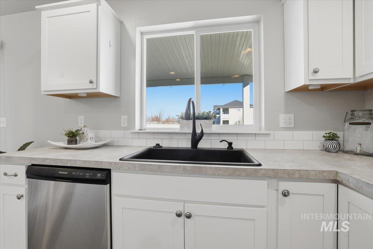 Kitchen with dishwasher, light countertops, and white cabinetry
