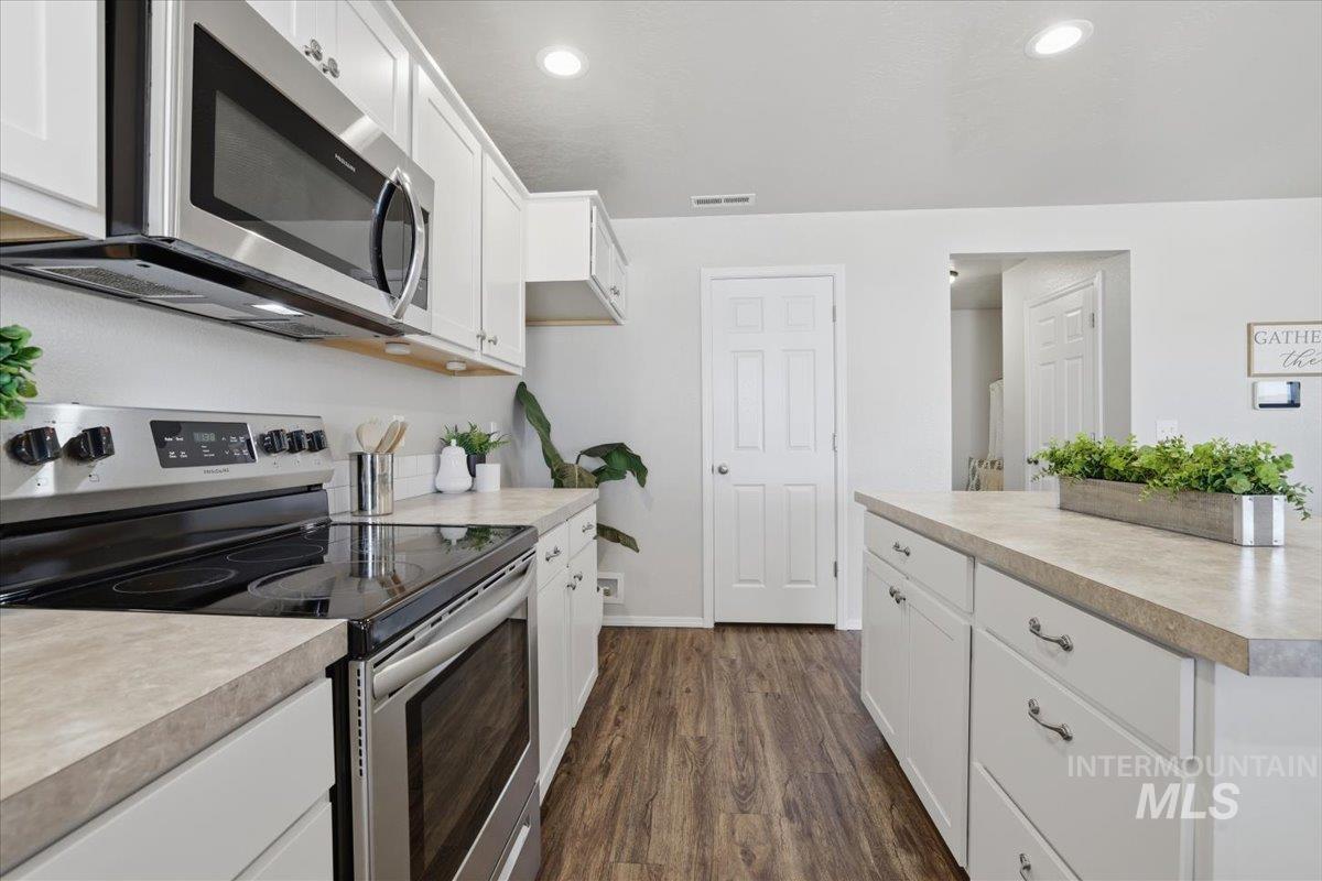 Kitchen featuring stainless steel appliances, white cabinetry, light countertops, and recessed lighting