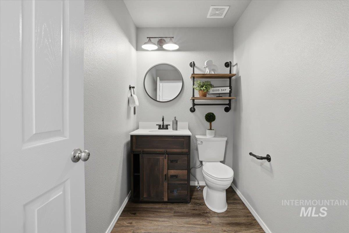 Half bath with vanity, dark wood-style flooring, and a textured wall