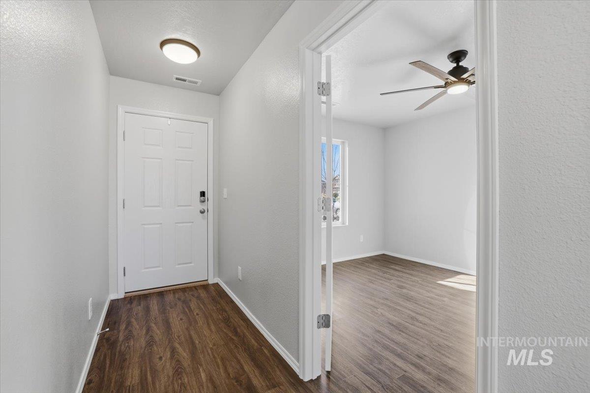 Doorway with a textured wall, wood finished floors, ceiling fan, and a textured ceiling