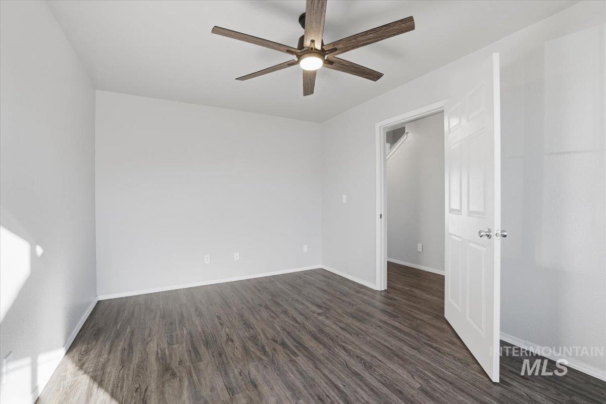 Unfurnished bedroom with dark wood-style floors and a ceiling fan