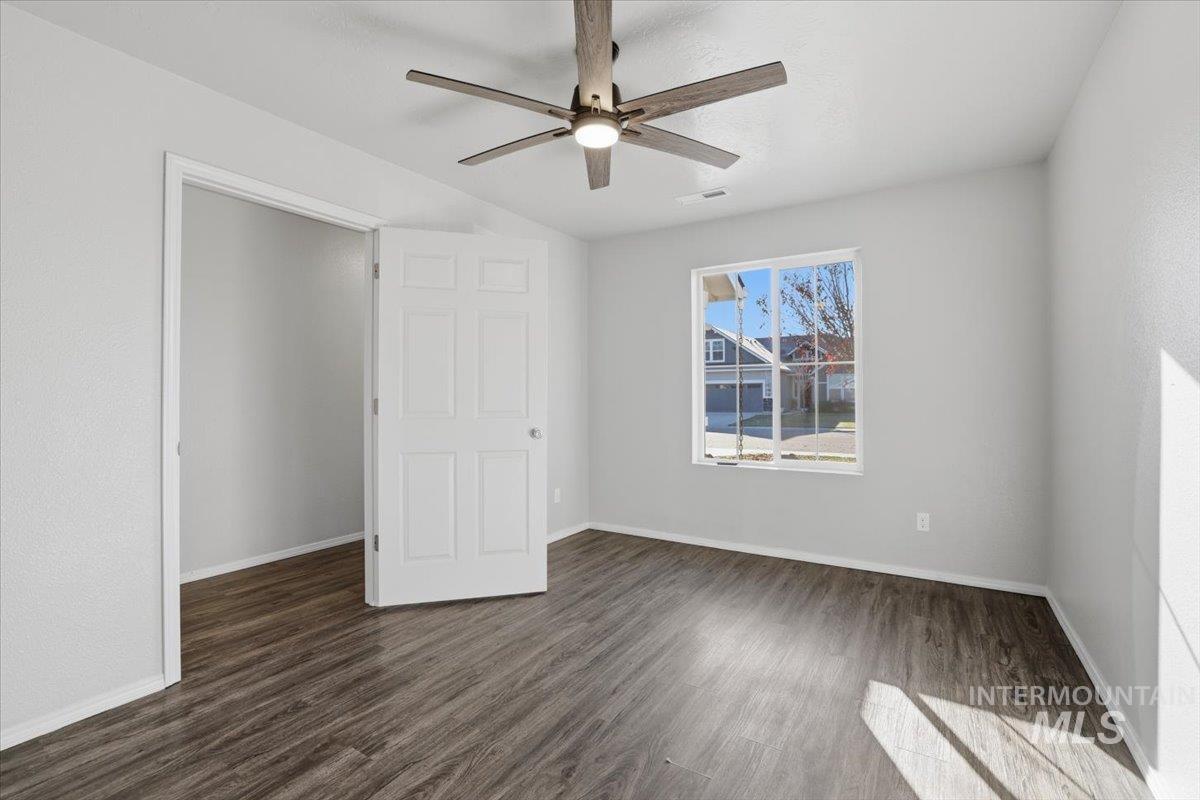 Unfurnished bedroom featuring dark wood-style flooring and a ceiling fan