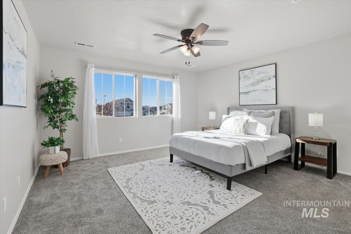 Carpeted bedroom with a ceiling fan and baseboards