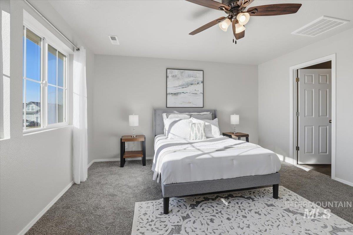 Carpeted bedroom with a ceiling fan and baseboards