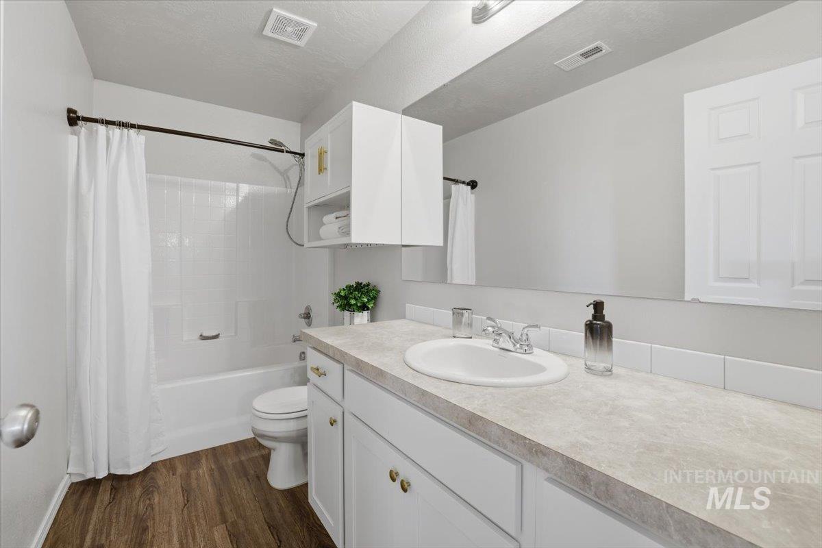 Bathroom featuring shower / bath combo, vanity, dark wood finished floors, and a textured ceiling