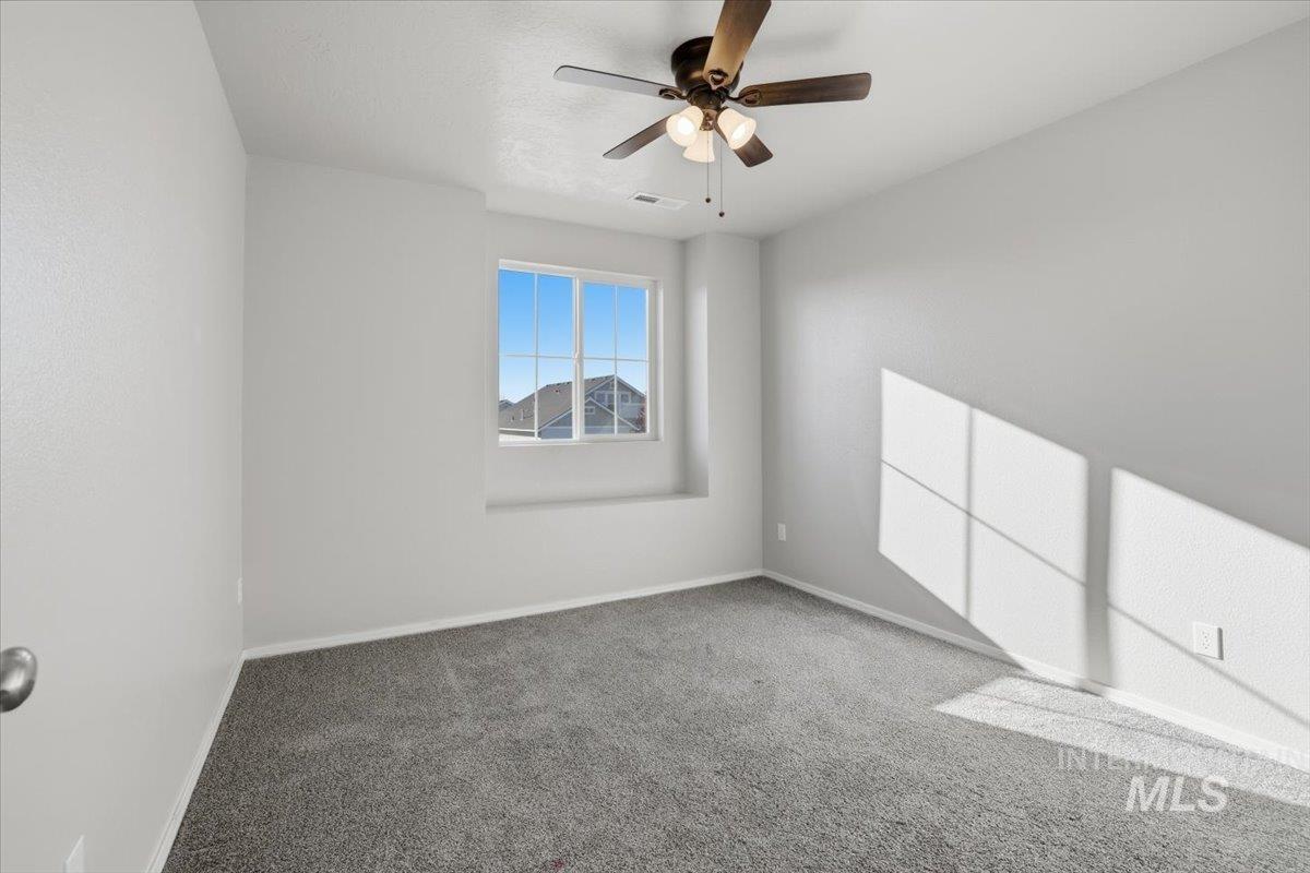 Carpeted spare room featuring baseboards and a ceiling fan