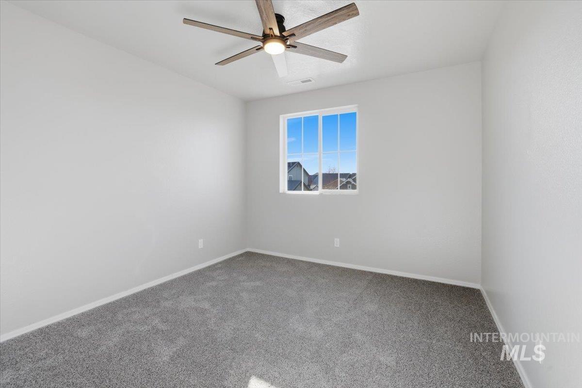 Carpeted spare room with baseboards and ceiling fan