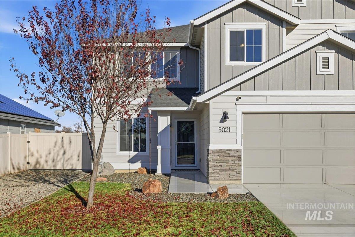 Craftsman inspired home with board and batten siding, a garage, roof with shingles, and stone siding