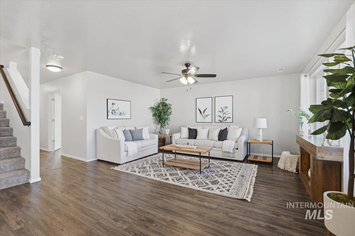 Living area with stairway, dark wood-style floors, and a ceiling fan