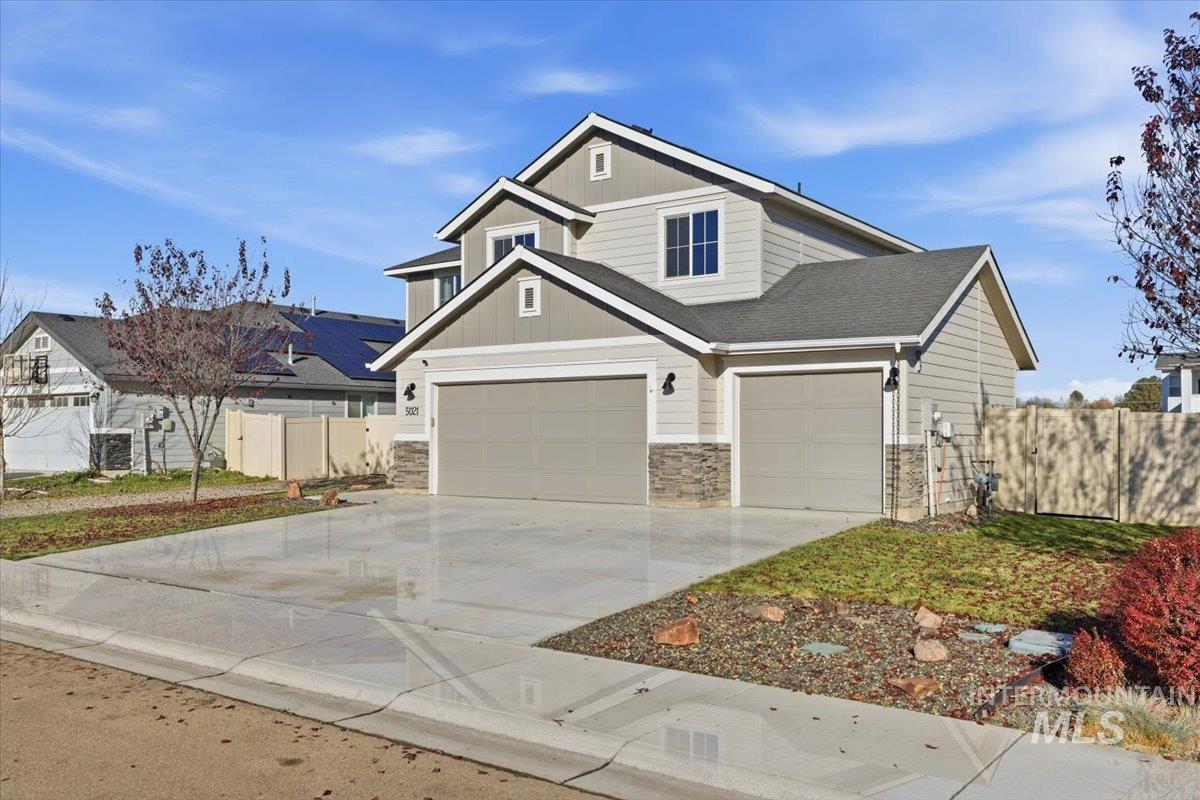 View of front of property featuring concrete driveway, stone siding, an attached garage, and a shingled roof