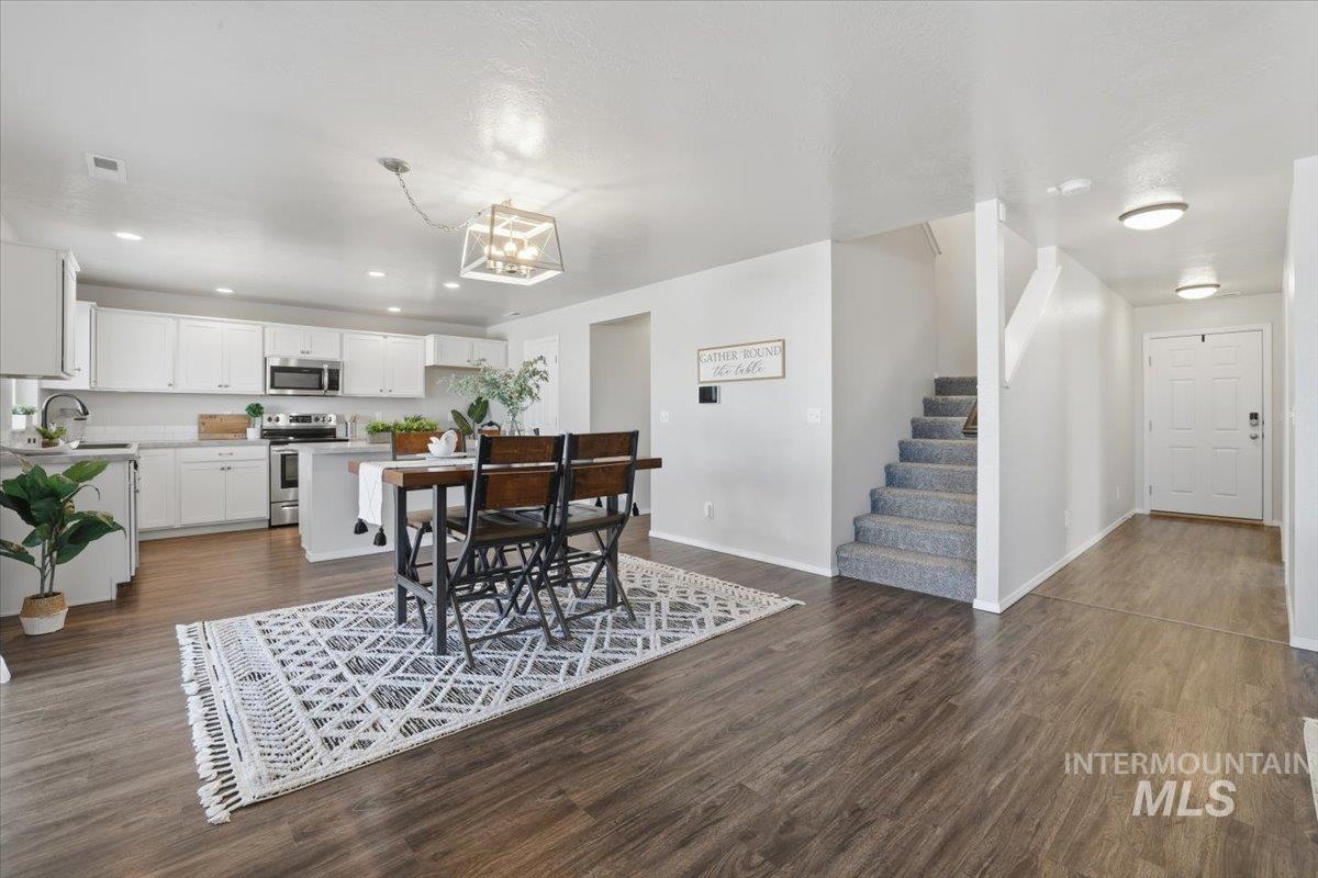 Dining room with stairway, recessed lighting, dark wood-style floors, and a chandelier