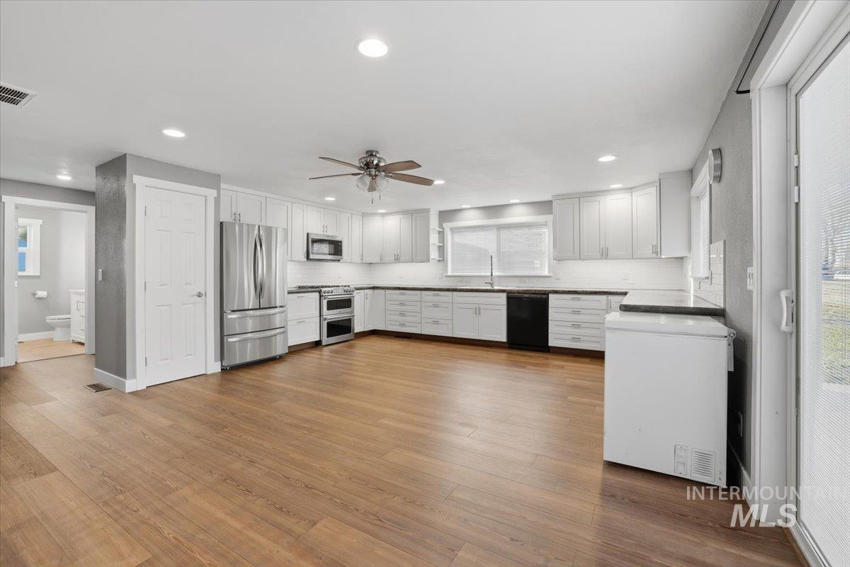 Kitchen with appliances with stainless steel finishes, white cabinetry, dark wood finished floors, a ceiling fan, and recessed lighting