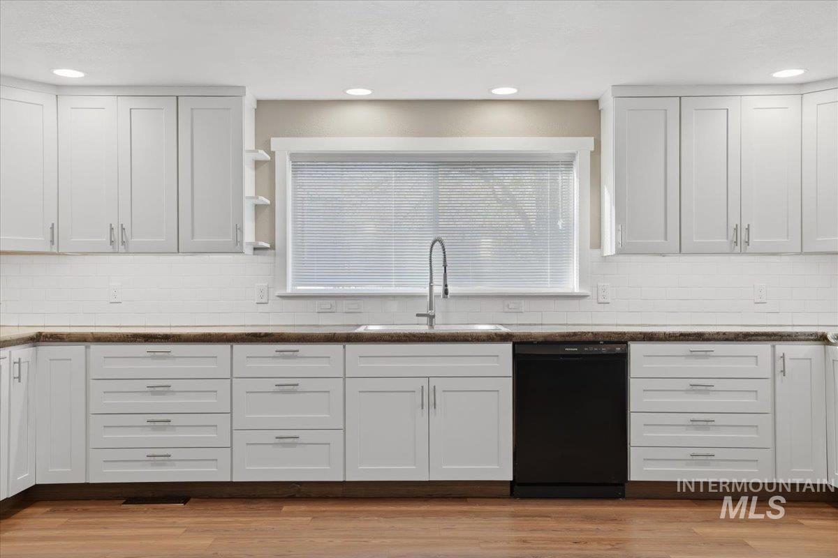 Kitchen featuring white cabinetry, black dishwasher, open shelves, tasteful backsplash, and recessed lighting