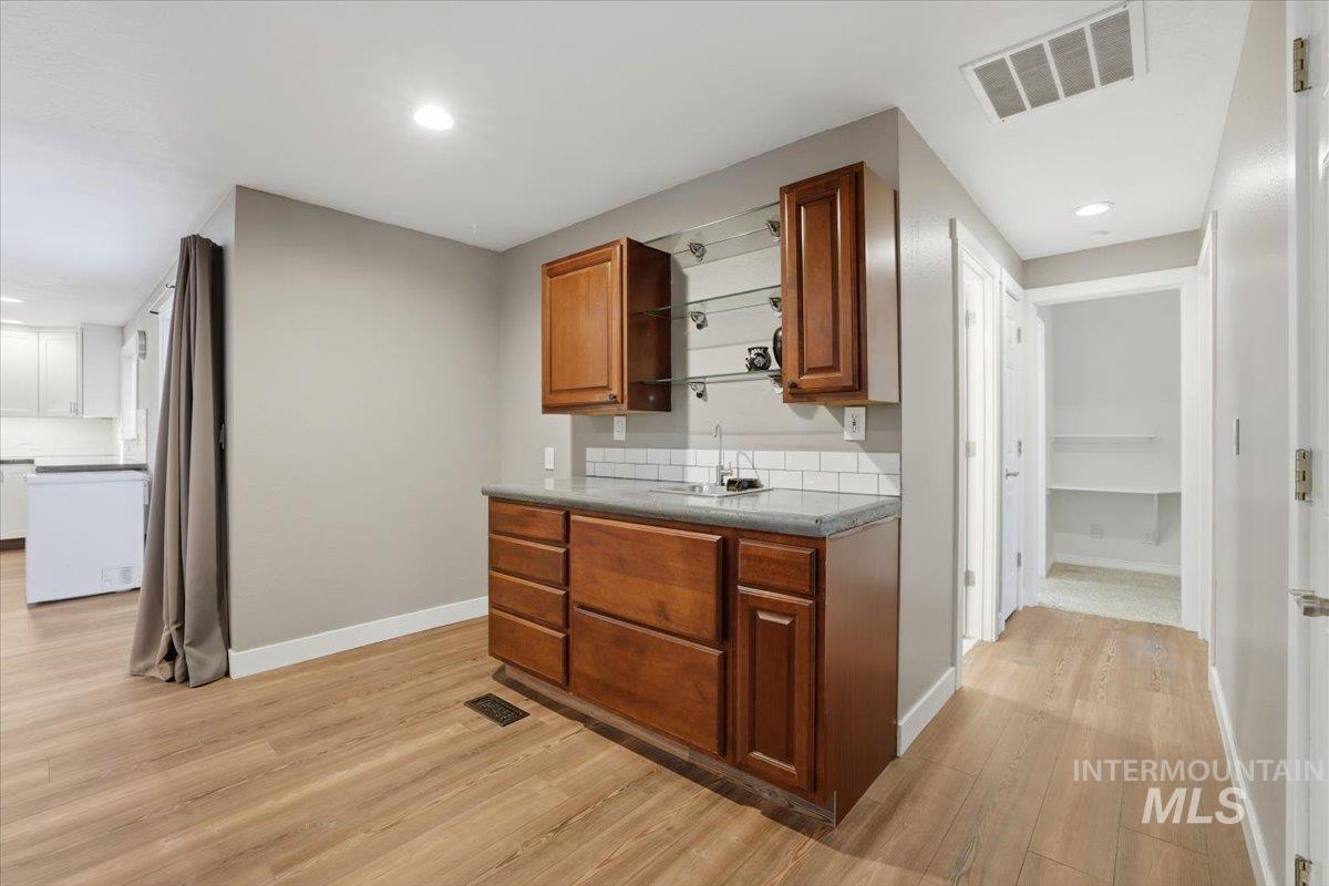 Kitchen with light wood-style flooring, brown cabinetry, recessed lighting, and open shelves
