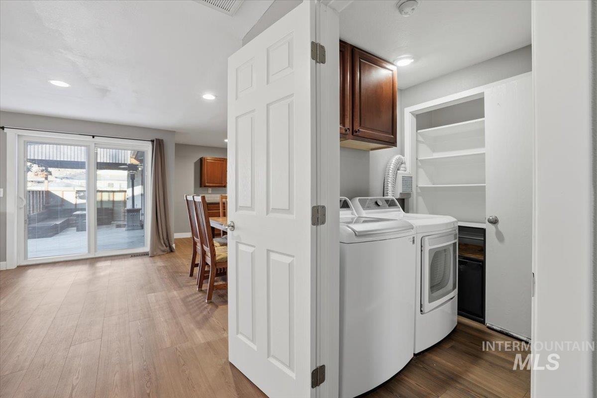 Laundry area with separate washer and dryer, dark wood-style floors, recessed lighting, and cabinet space