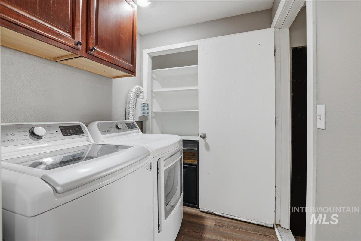 Washroom featuring washing machine and dryer, dark wood-style floors, and cabinet space