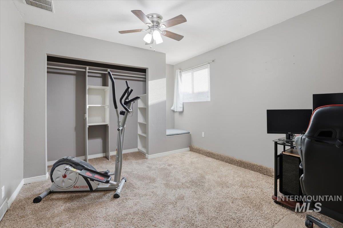 Workout room featuring light carpet and a ceiling fan