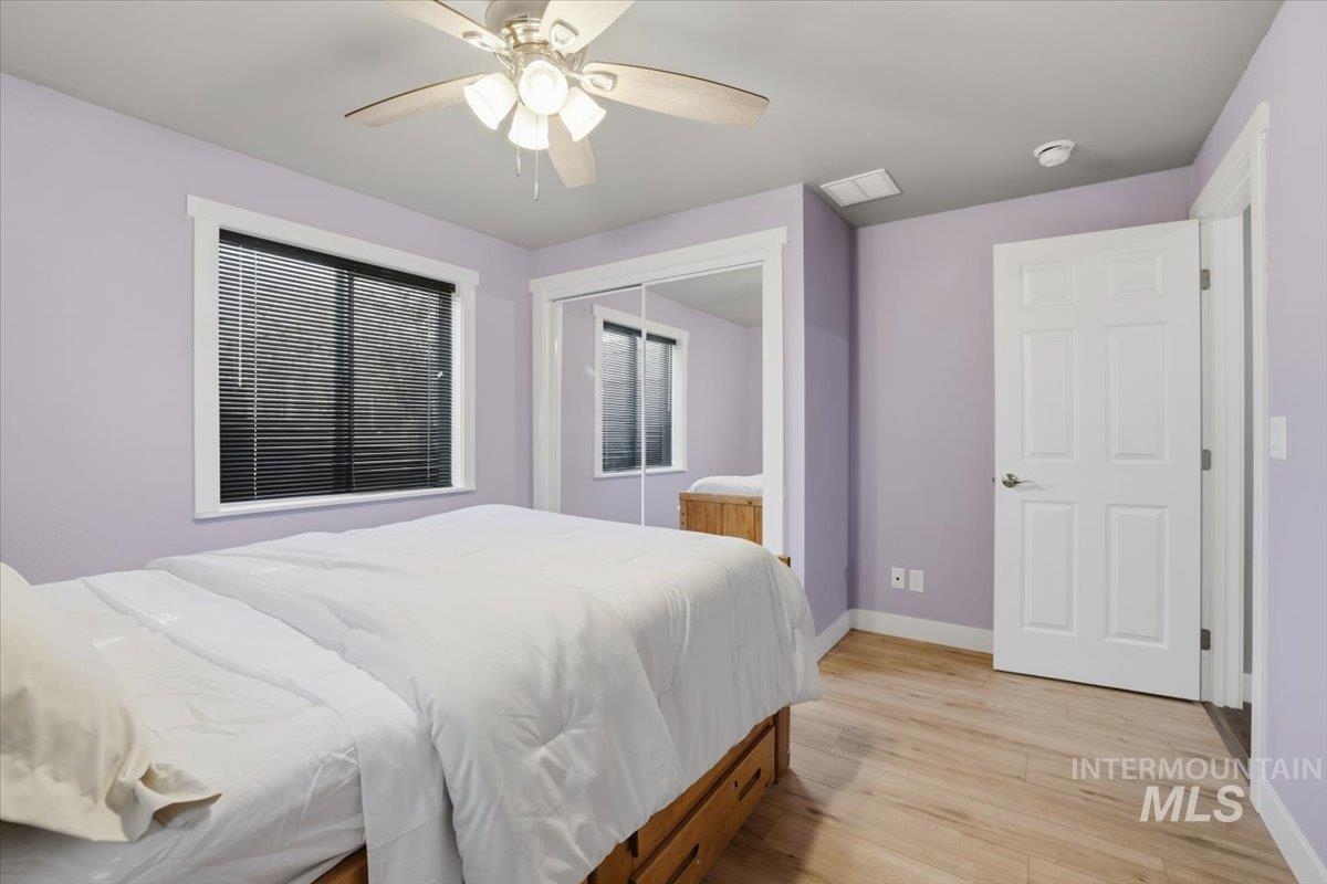 Bedroom with light wood-style floors, ceiling fan, and a closet