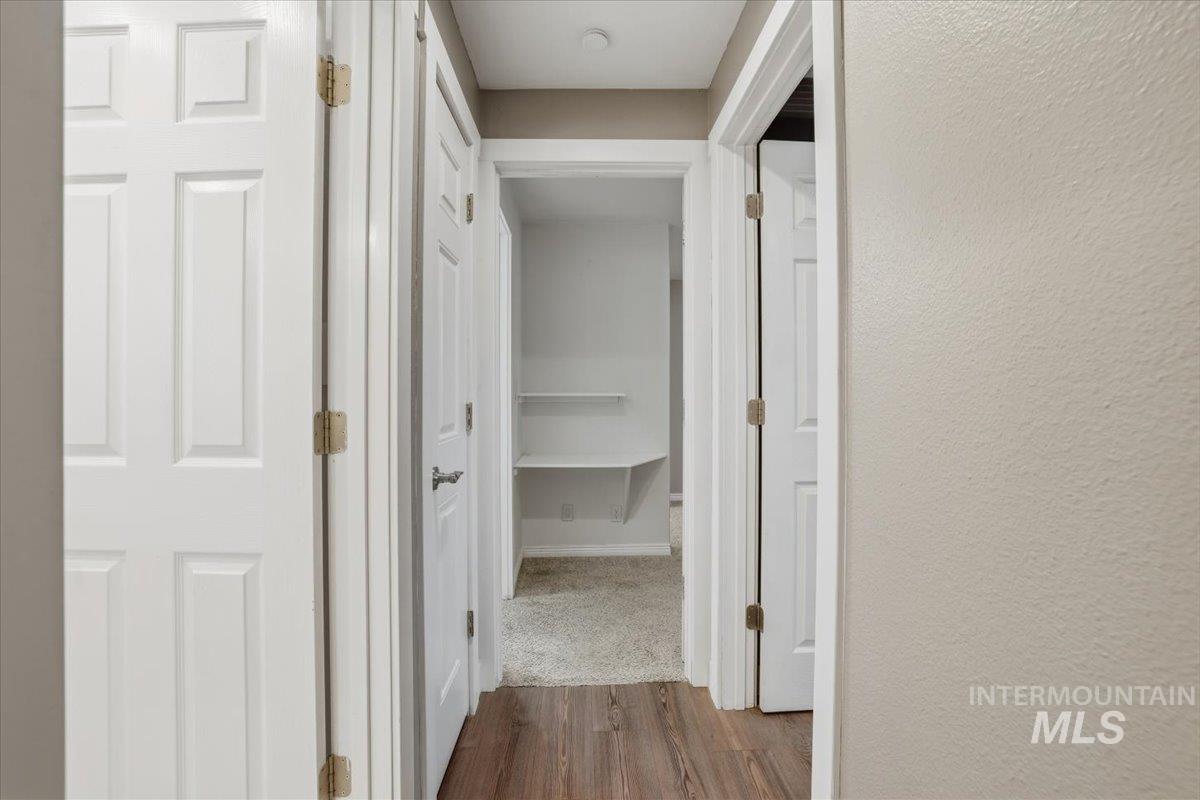 Hall featuring dark wood-type flooring and a textured wall