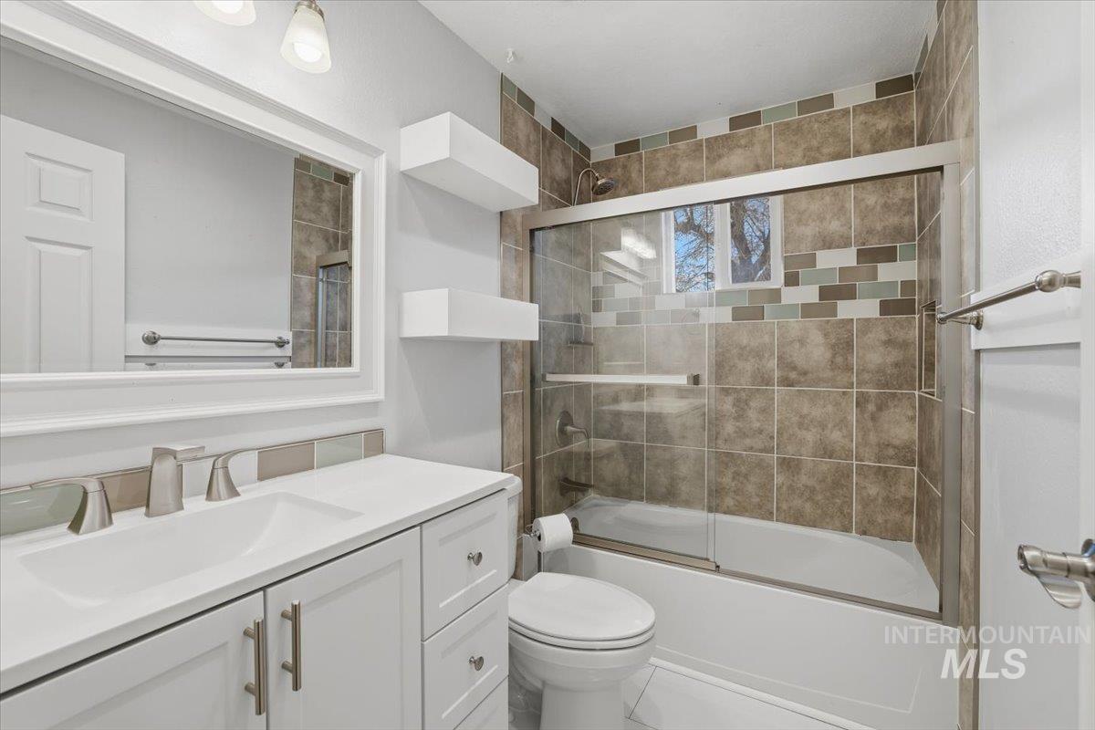 Full bath featuring bath / shower combo with glass door, vanity, and tile patterned floors