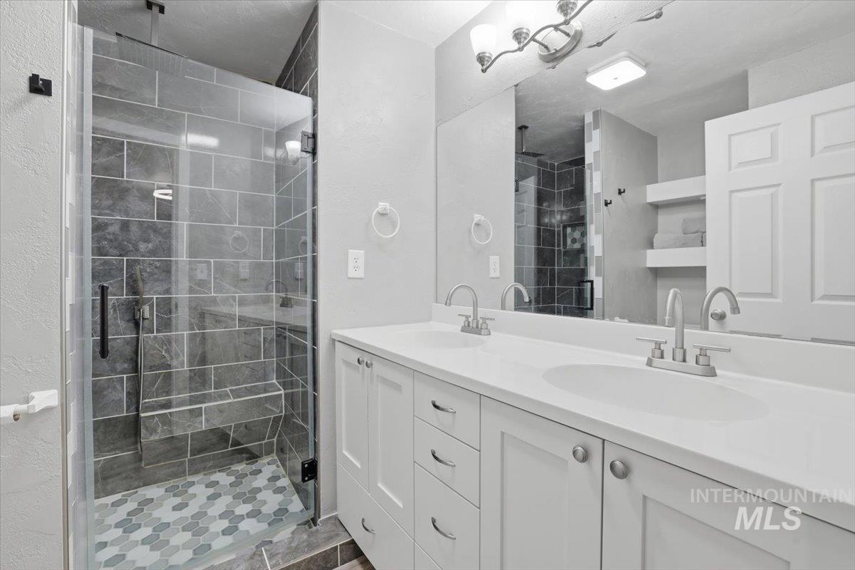 Bathroom featuring double vanity, a shower stall, and a textured wall