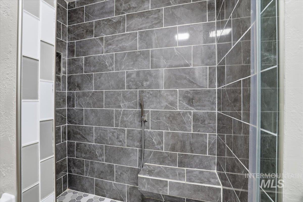 Full bathroom featuring tiled shower and a textured wall