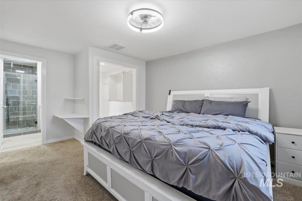 Carpeted bedroom featuring ensuite bathroom and baseboards