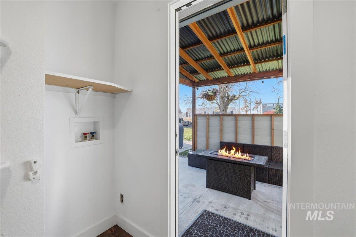 Laundry room featuring a warm lit fireplace, wood finished floors, and washer hookup