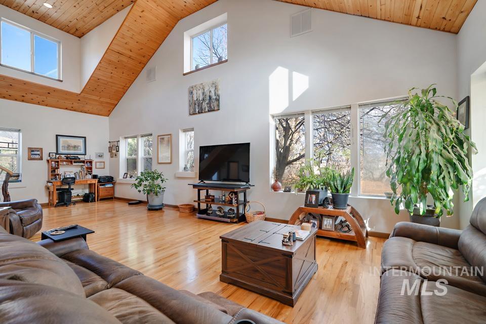 Living area featuring wooden ceiling, high vaulted ceiling, and light wood-style flooring