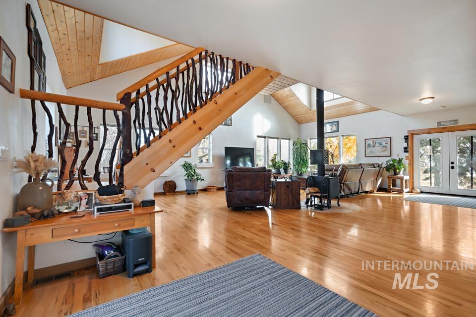 Living area with a wood stove, french doors, wooden ceiling, wood finished floors, and plenty of natural light