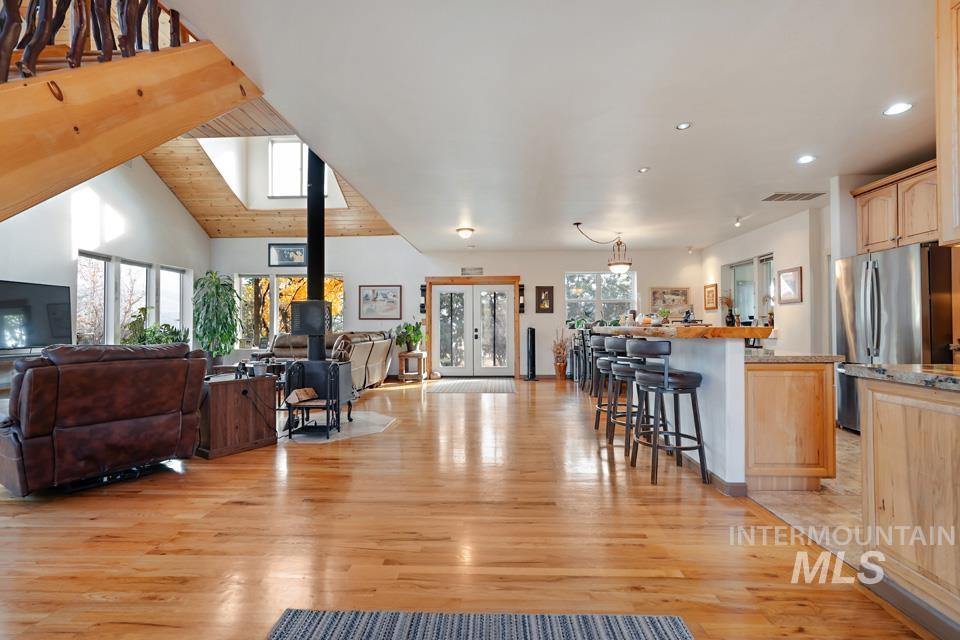 Living area featuring light wood-type flooring, french doors, a wood stove, wood ceiling, and lofted ceiling