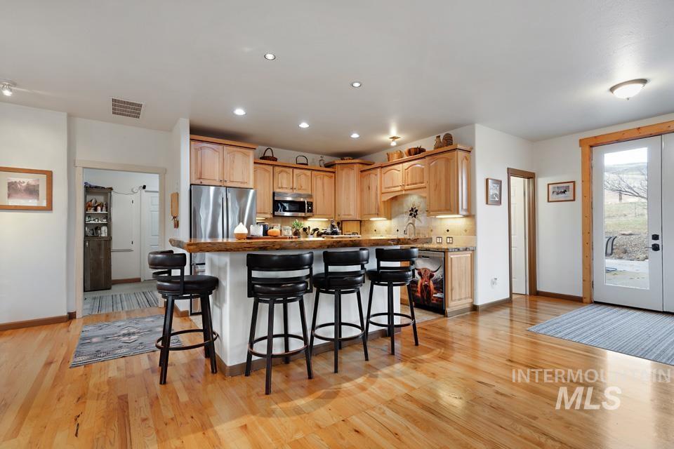 Kitchen with a breakfast bar, appliances with stainless steel finishes, a kitchen island, light brown cabinetry, and french doors