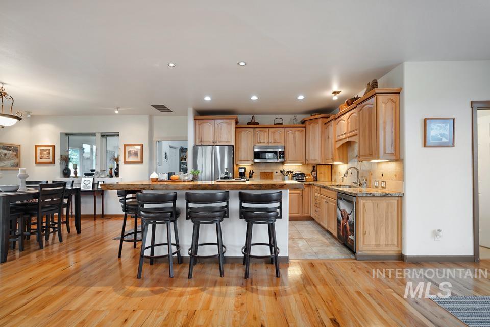 Kitchen featuring a kitchen bar, stainless steel appliances, light wood-style flooring, recessed lighting, and a kitchen island