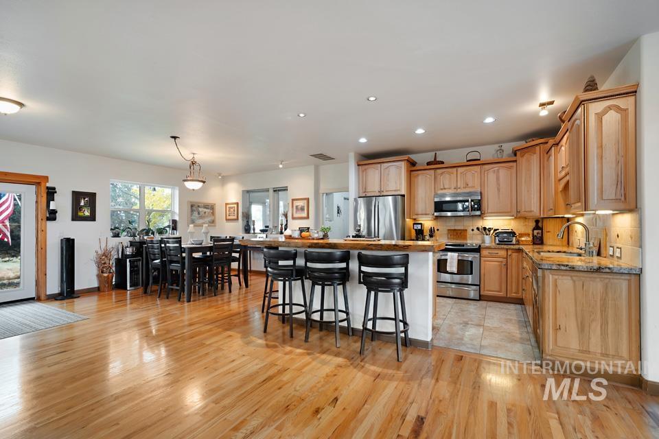 Kitchen featuring stainless steel appliances, a kitchen breakfast bar, a kitchen island, decorative light fixtures, and decorative backsplash
