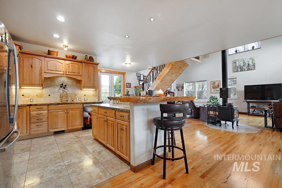 Kitchen featuring a kitchen bar, a wood stove, open floor plan, recessed lighting, and freestanding refrigerator