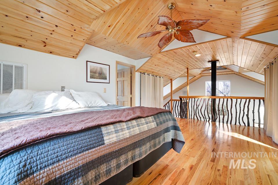 Bedroom with wood ceiling, vaulted ceiling, light wood finished floors, and ceiling fan