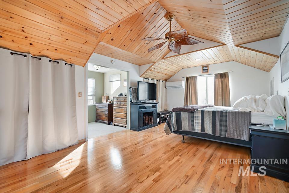 Bedroom featuring wooden ceiling, multiple windows, light wood-style flooring, a ceiling fan, and lofted ceiling