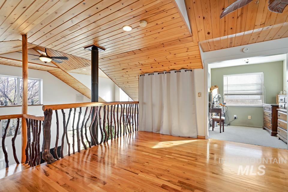 Hallway with light wood finished floors, wooden ceiling, and lofted ceiling