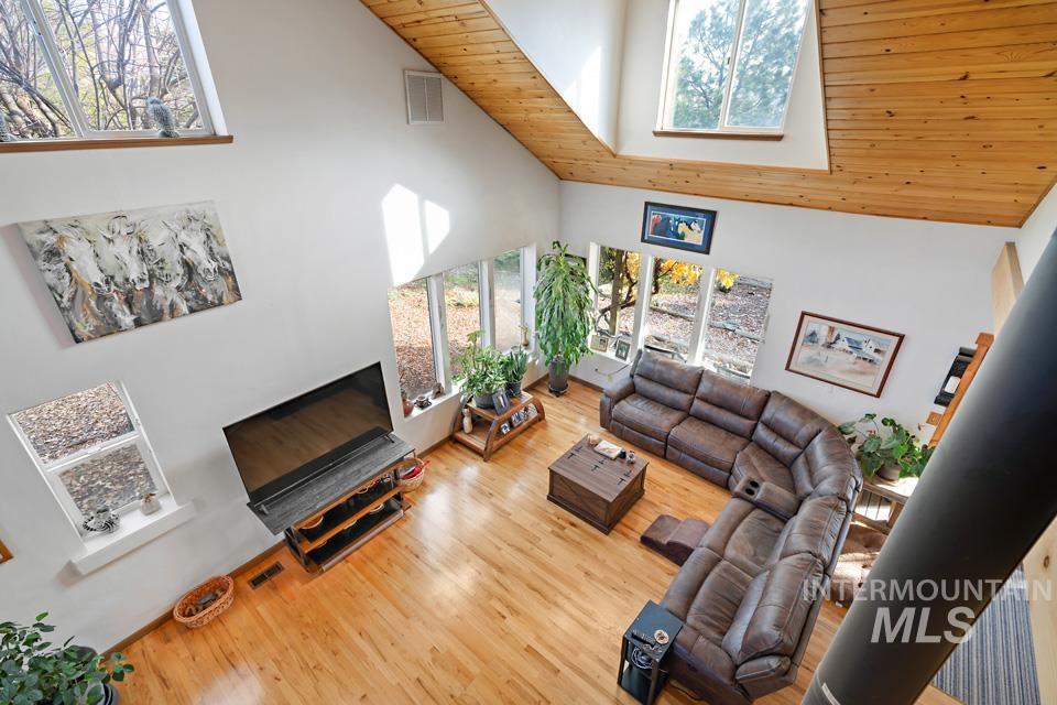Living room with high vaulted ceiling, wooden ceiling, wood finished floors, and a skylight