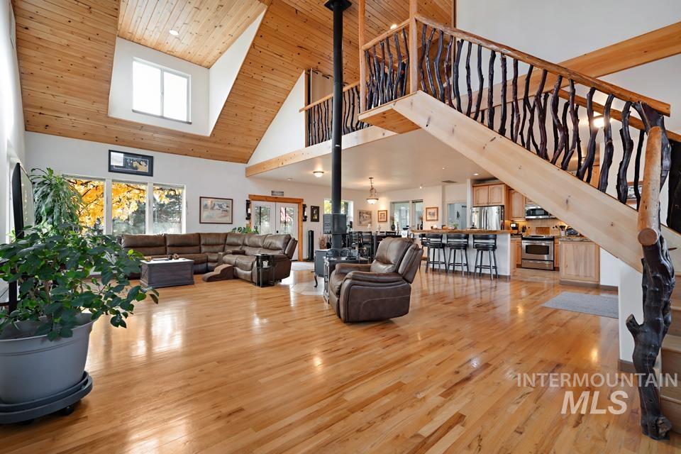 Living area with wooden ceiling, light wood finished floors, high vaulted ceiling, and stairway