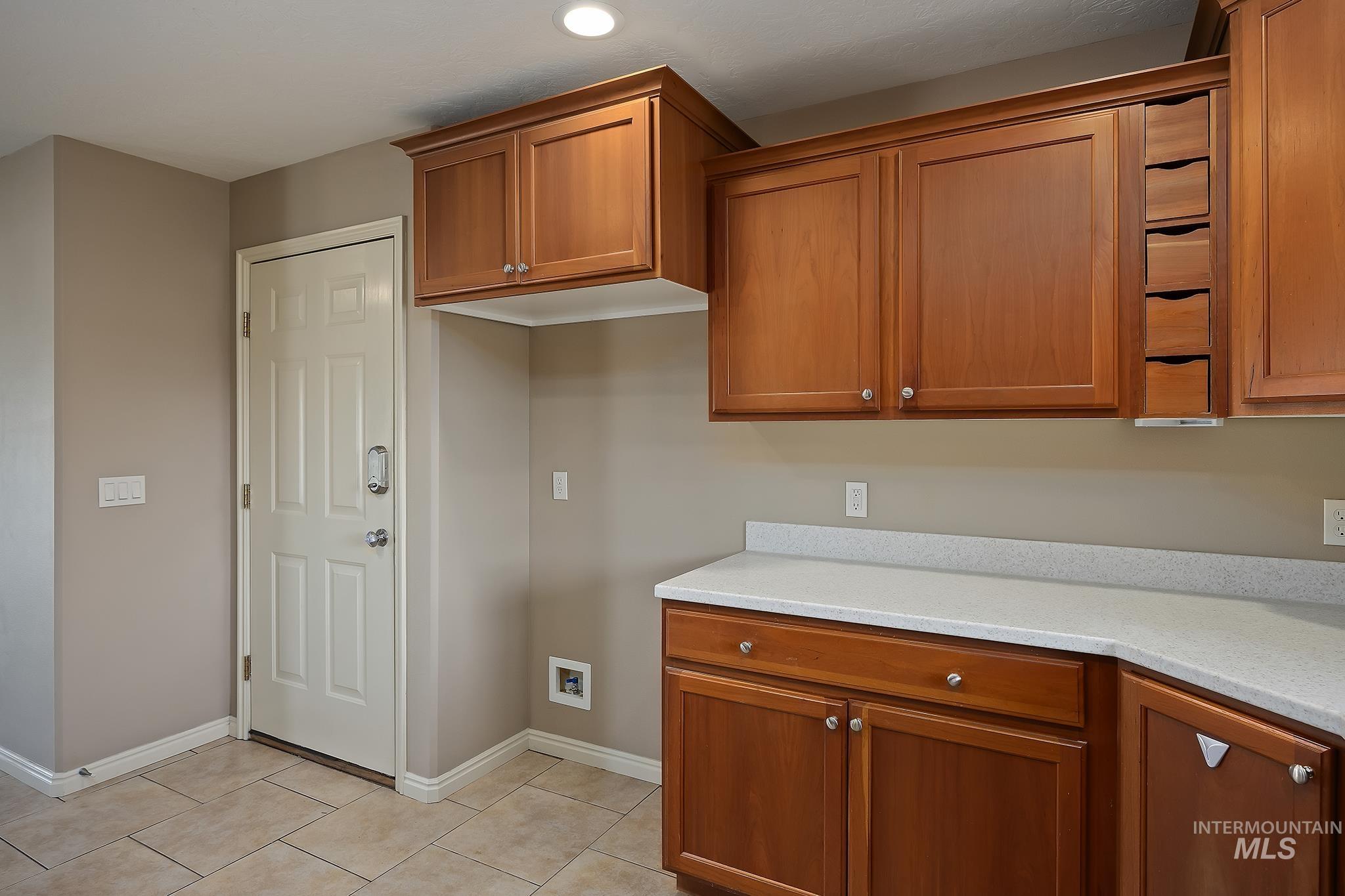 Kitchen featuring brown cabinets, light stone counters, and light tile patterned floors