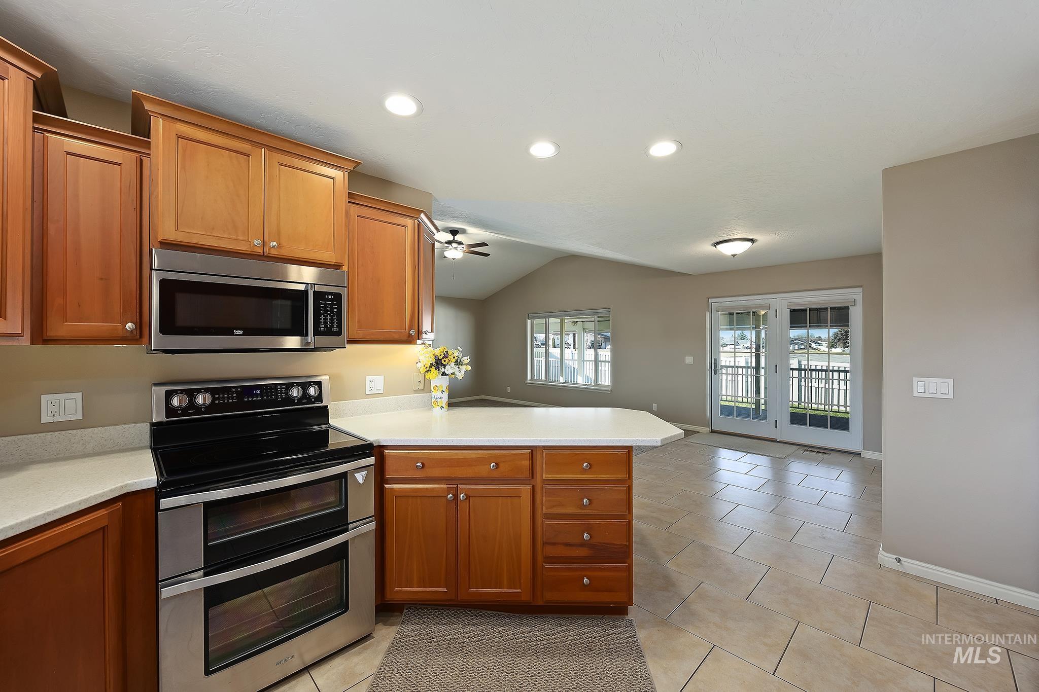 Kitchen with appliances with stainless steel finishes, a peninsula, recessed lighting, open floor plan, and light tile patterned flooring