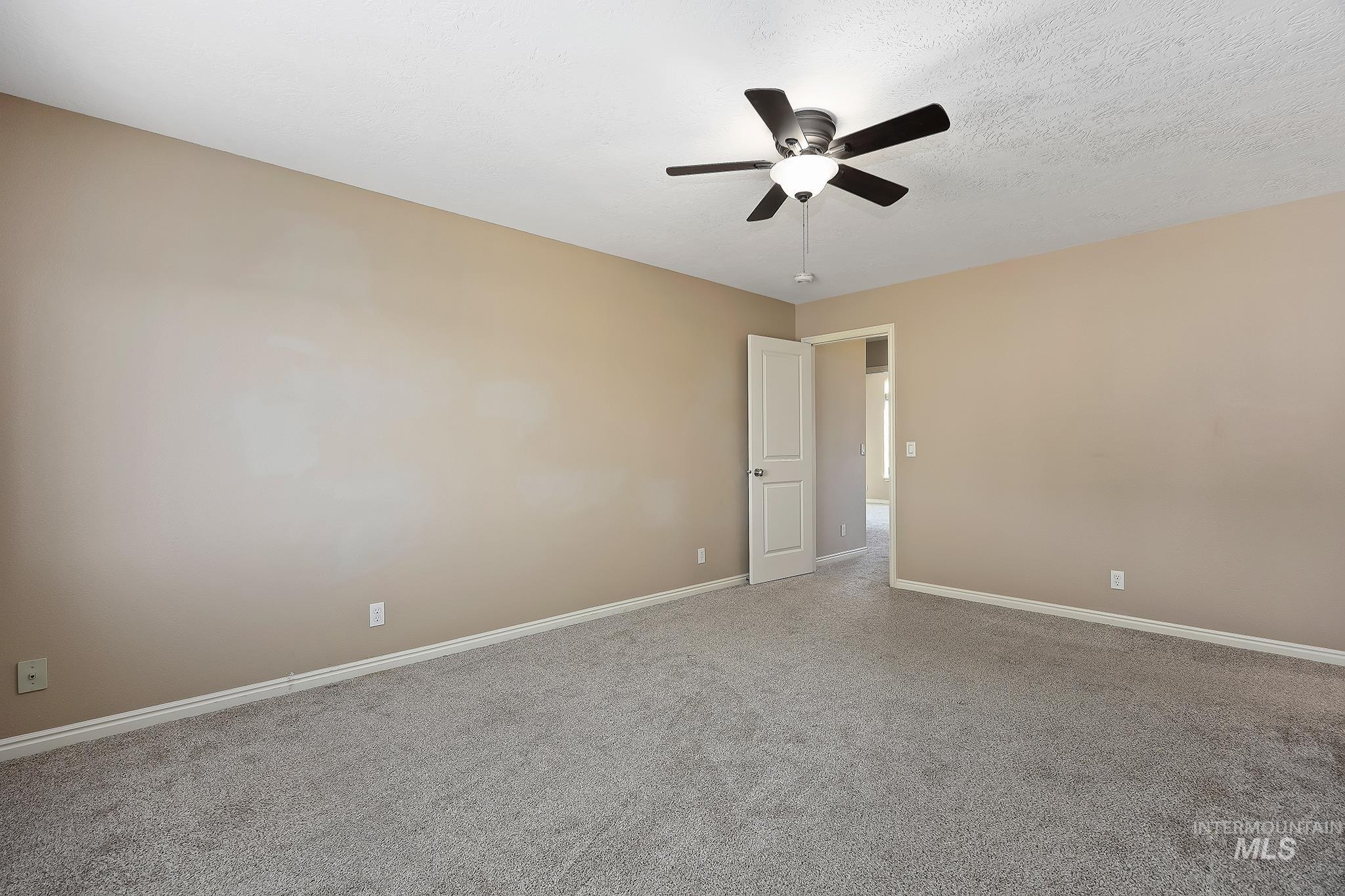 Spare room featuring carpet, ceiling fan, and a textured ceiling