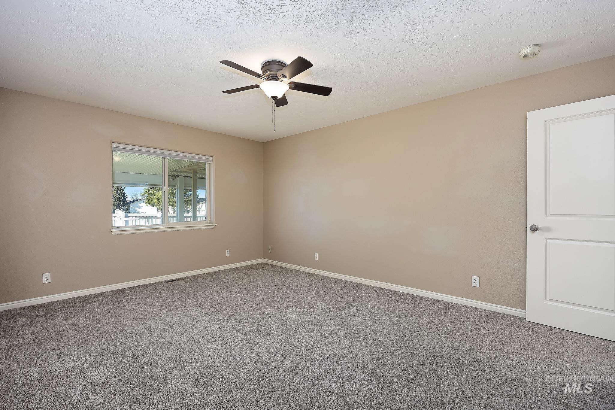 Unfurnished room featuring light colored carpet, ceiling fan, and a textured ceiling