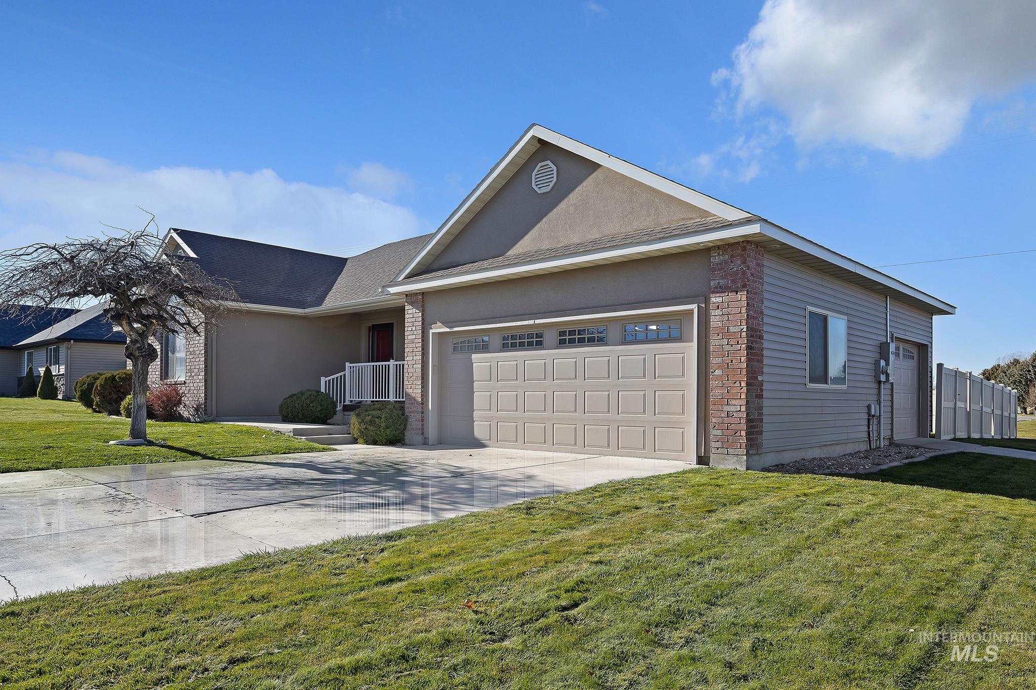 Ranch-style house featuring brick siding, concrete driveway, a front yard, a garage, and stucco siding