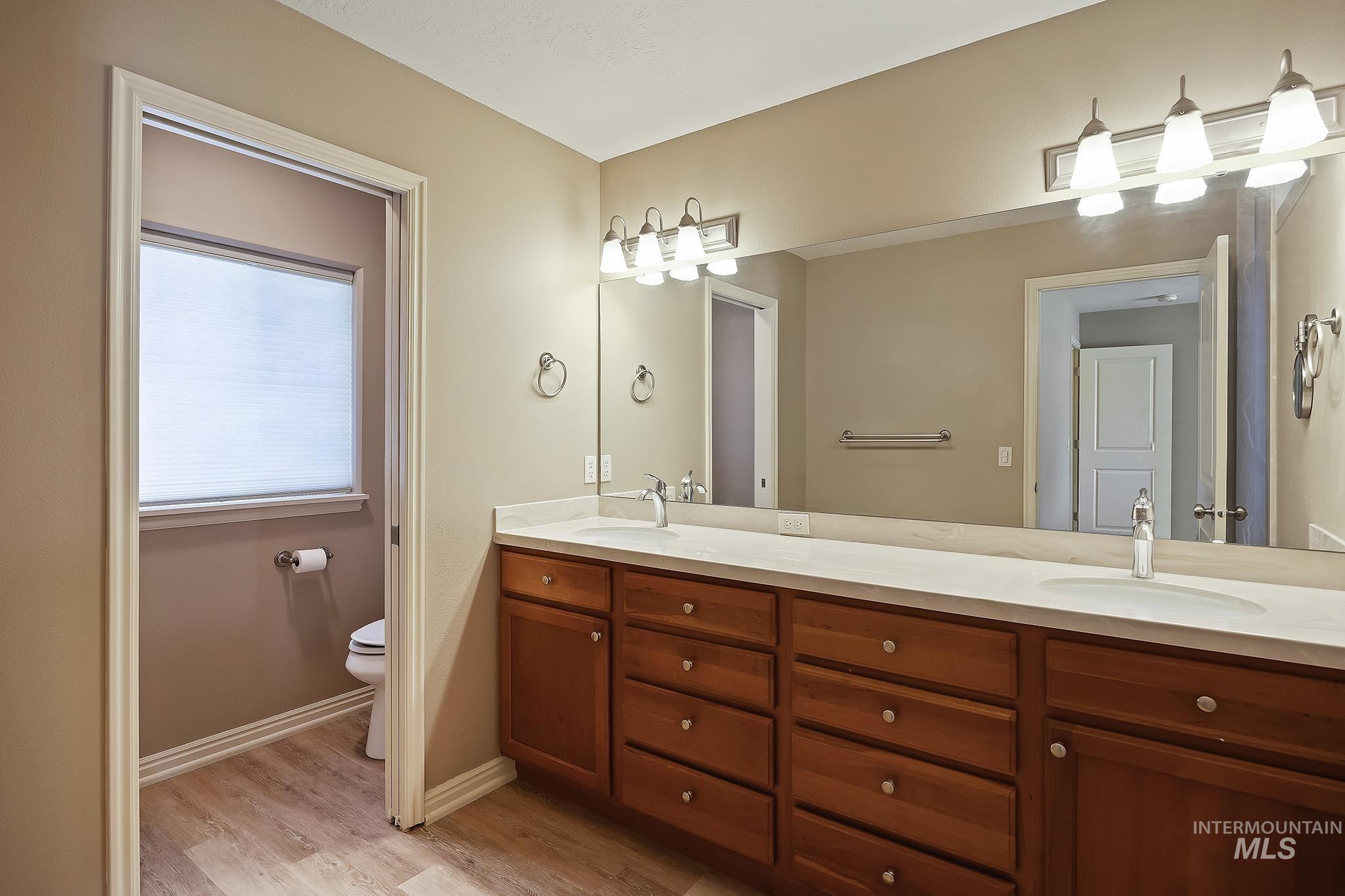 Full bathroom featuring double vanity and light wood-style floors