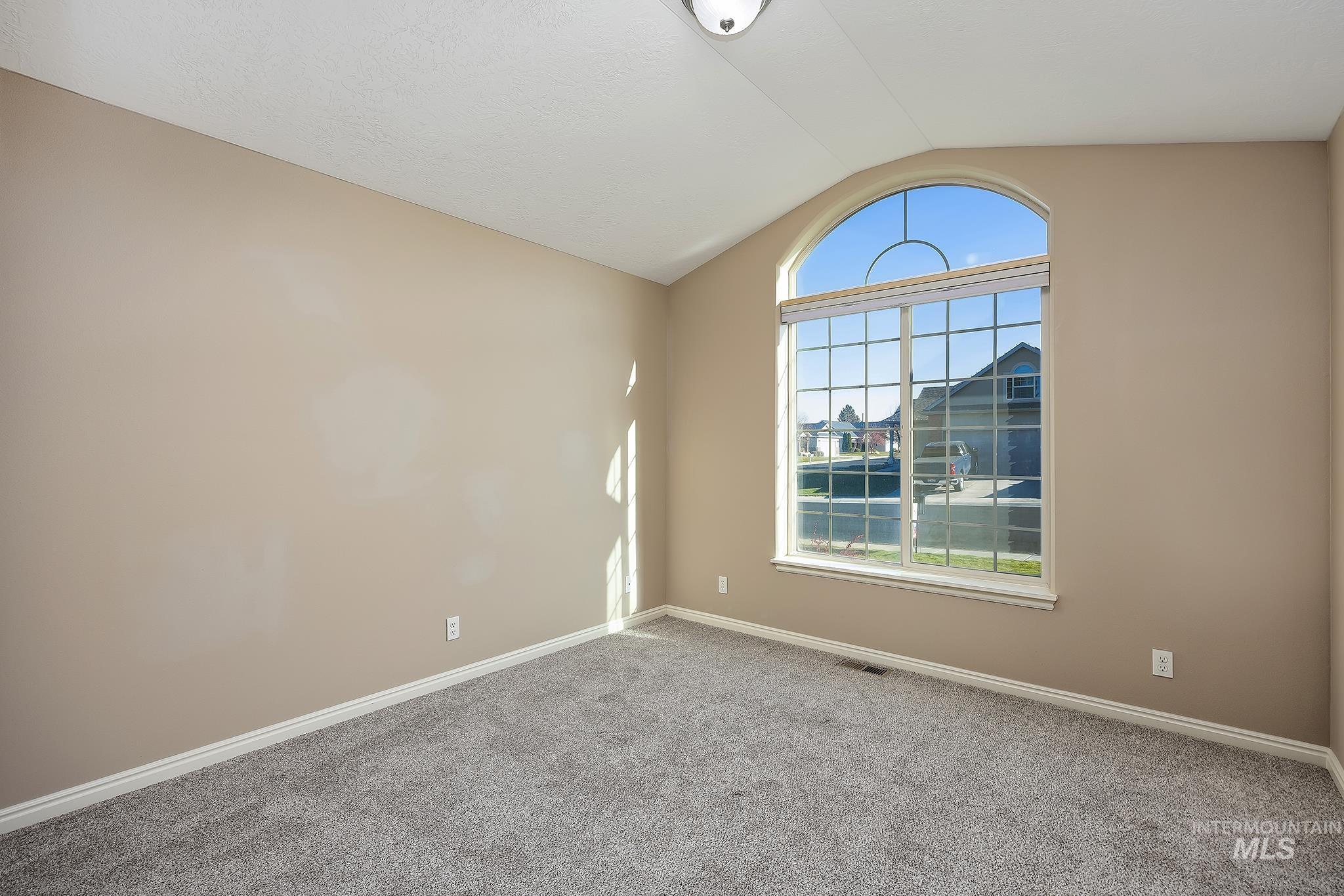 Unfurnished room featuring lofted ceiling and carpet flooring
