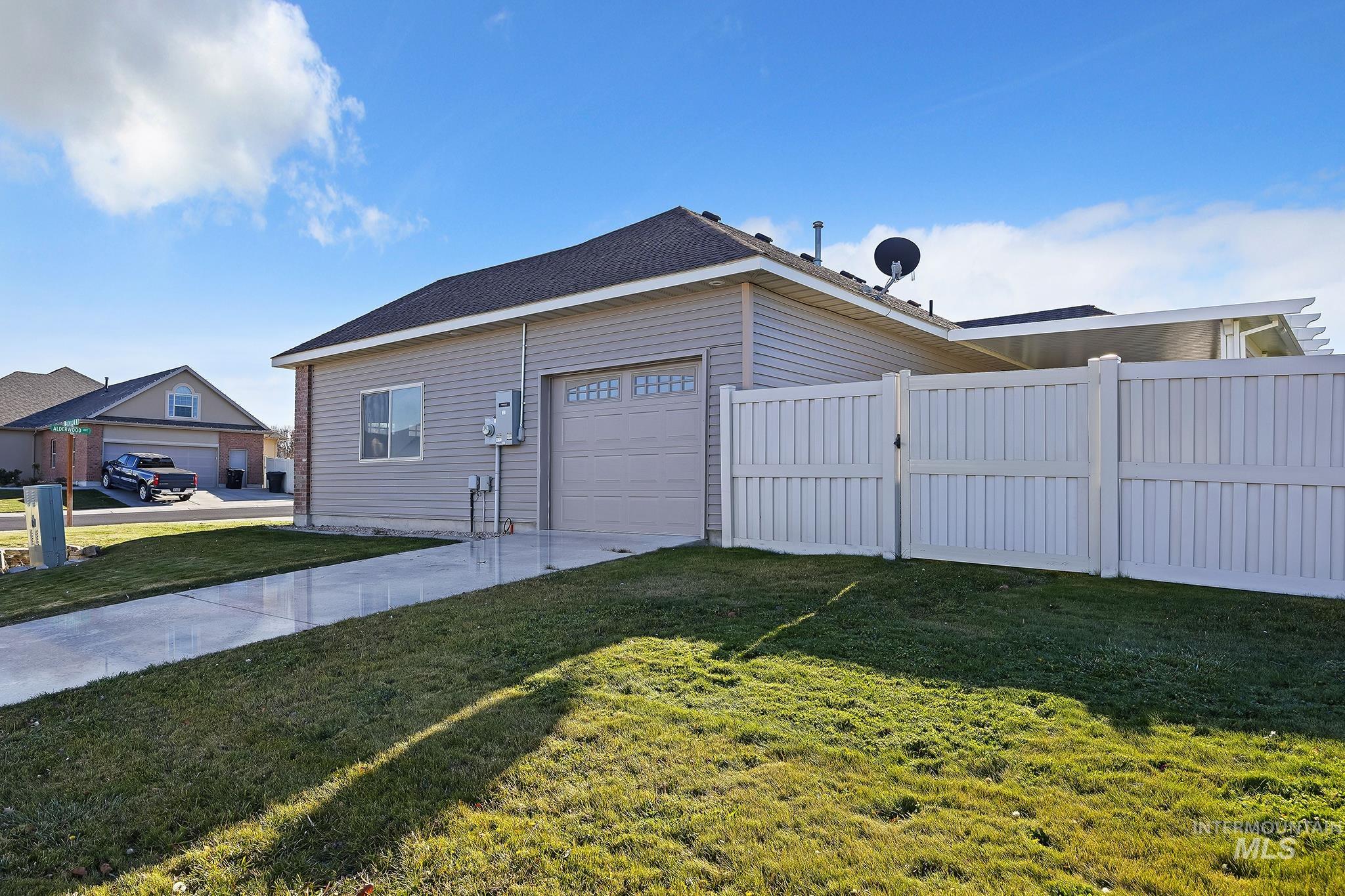 View of side of property featuring concrete driveway, an attached garage, and a shingled roof