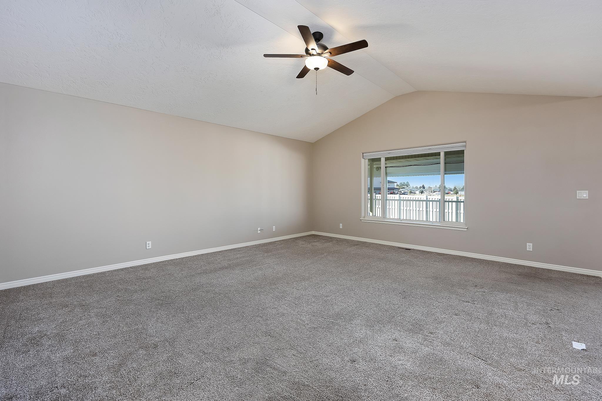 Empty room with lofted ceiling, carpet, and ceiling fan