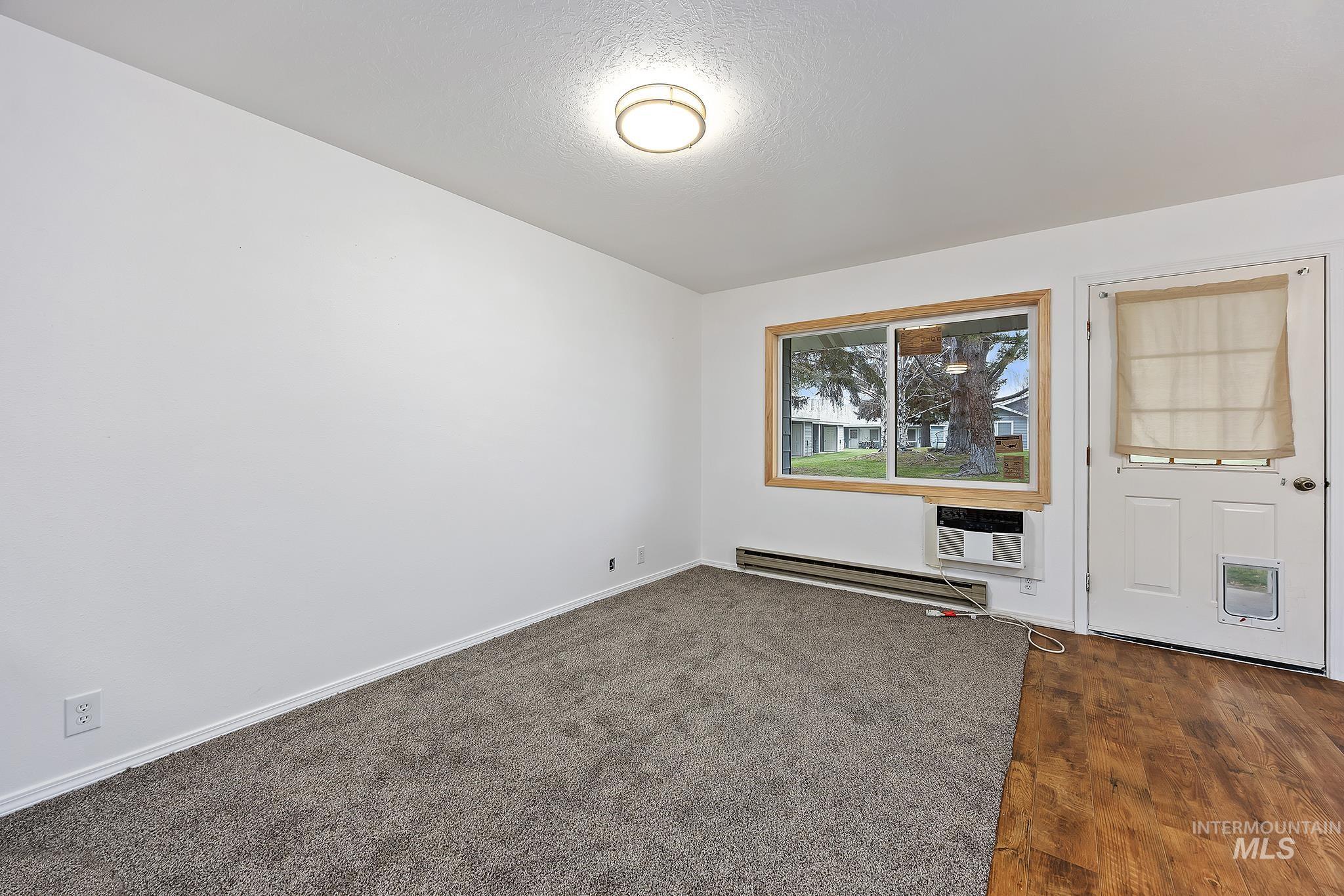 Unfurnished room with baseboard heating, a textured ceiling, and dark wood finished floors